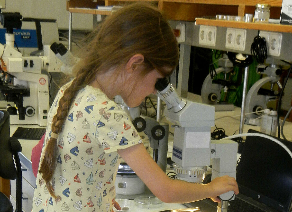 Mädchen guckt durch ein Mikroskop